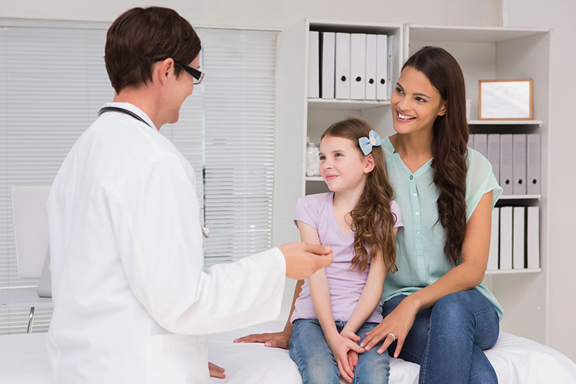 Doctor examining girl with mother