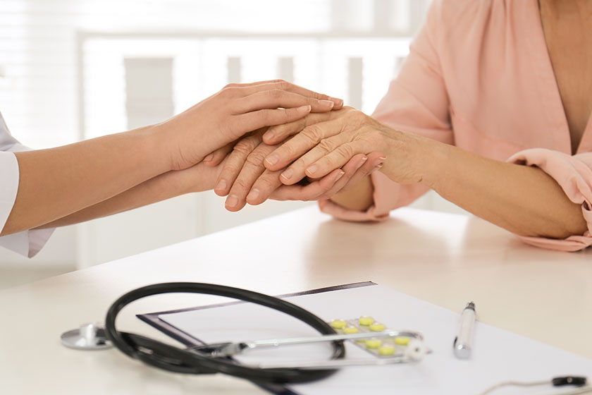 Doctor holding senior patient's hands in office