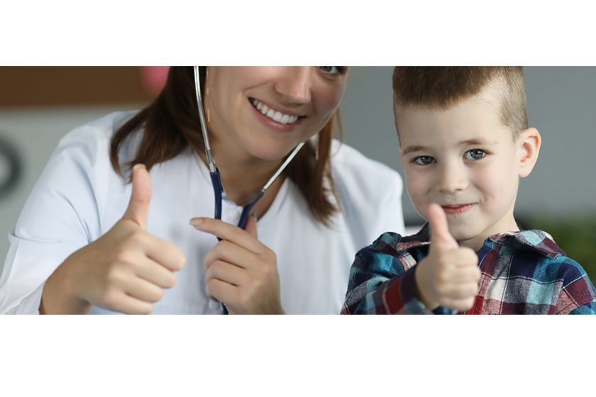 Young smiling doctor and child showing thumbs