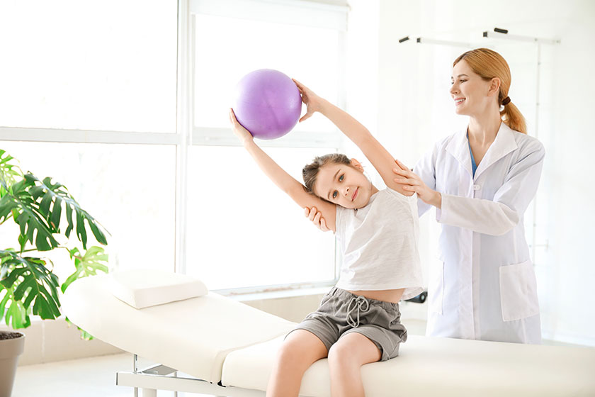 Physiotherapist working with little girl in rehabilitation