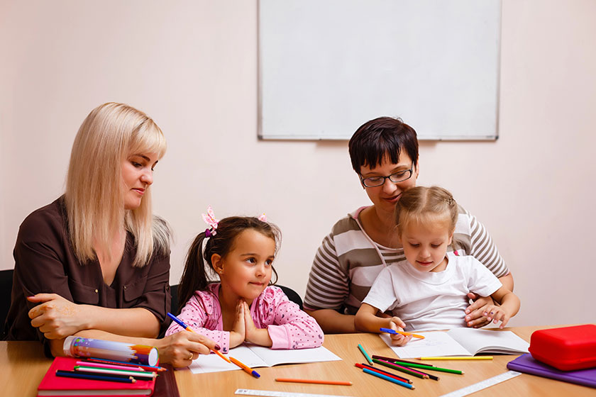 Two teachers working in class with their little pupils