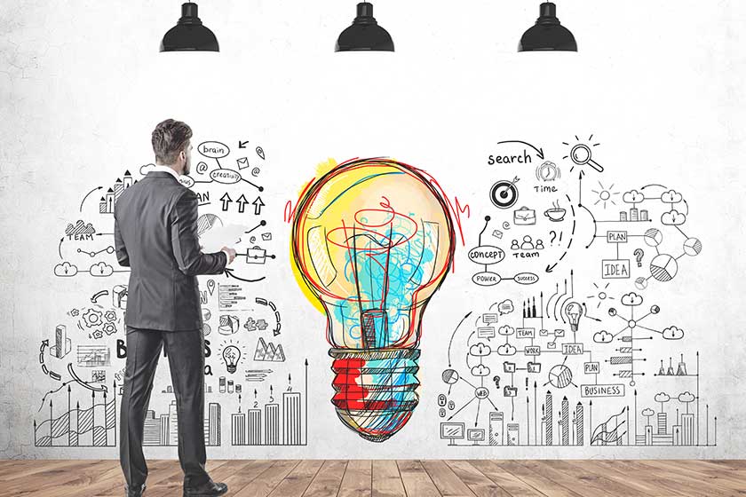 A concrete wall with a business plan sketch and a large light bulb